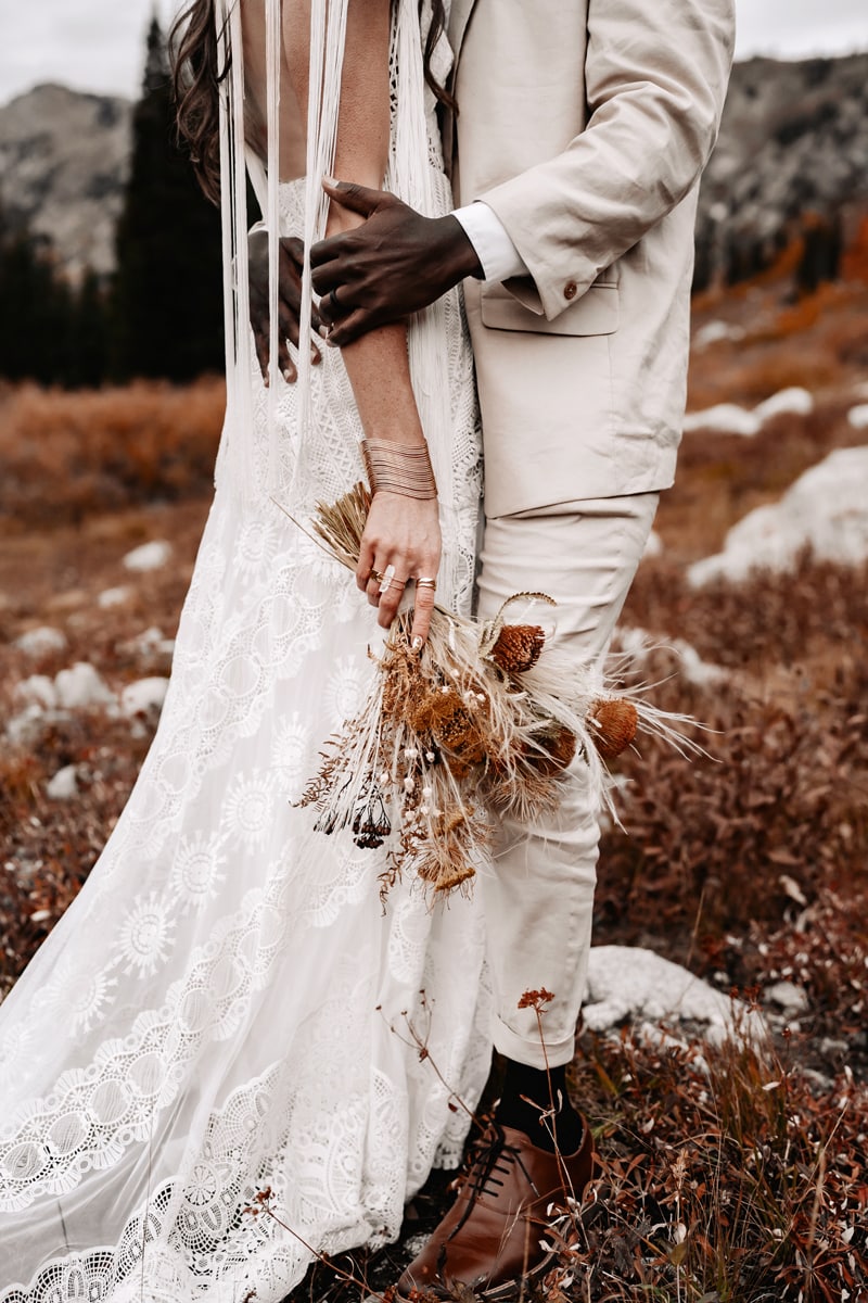 Wedding Photographer, bride and groom embrace as they stand in a mountain meadow