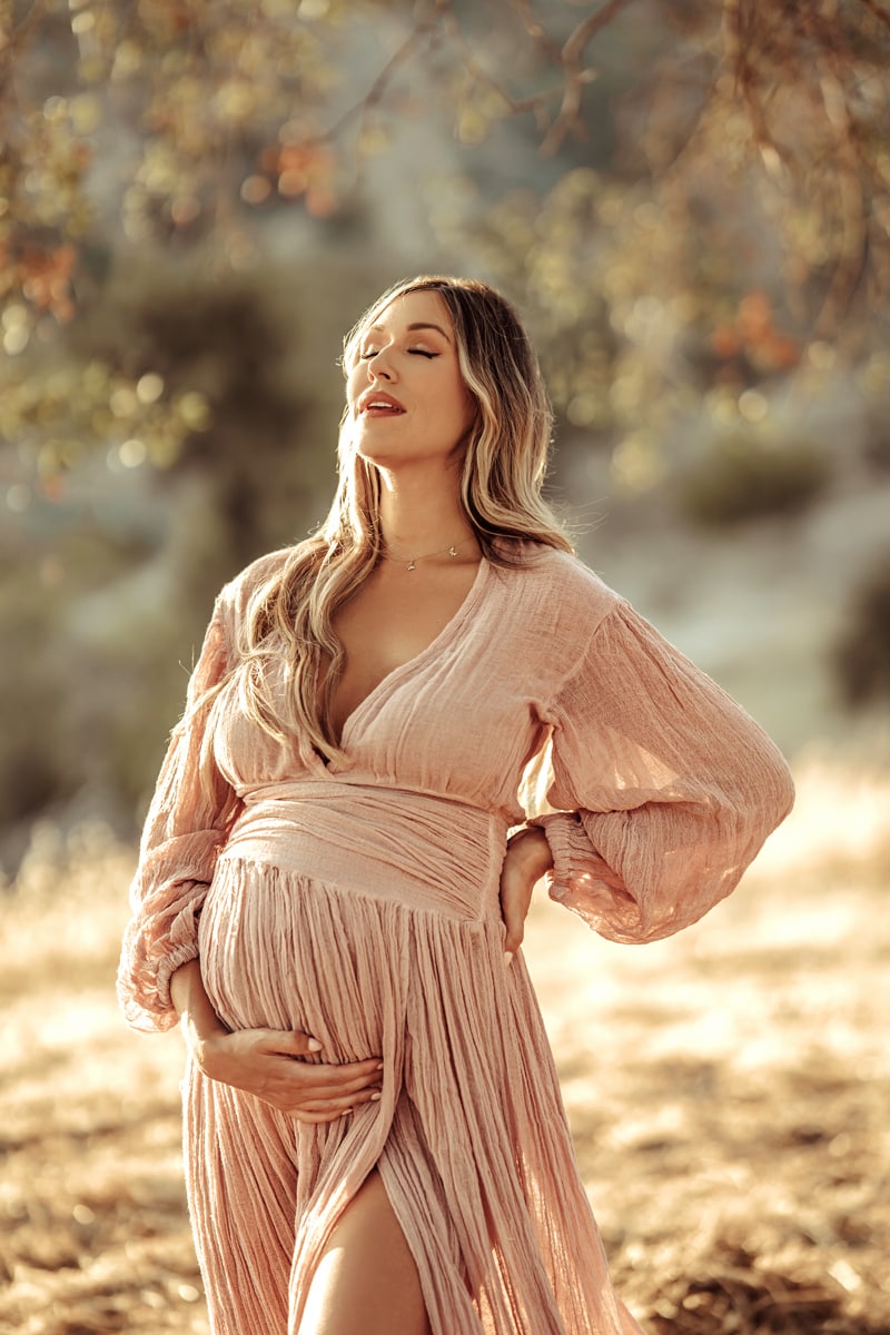 Maternity Photographer, pregnant woman in dress stands beneath tree
