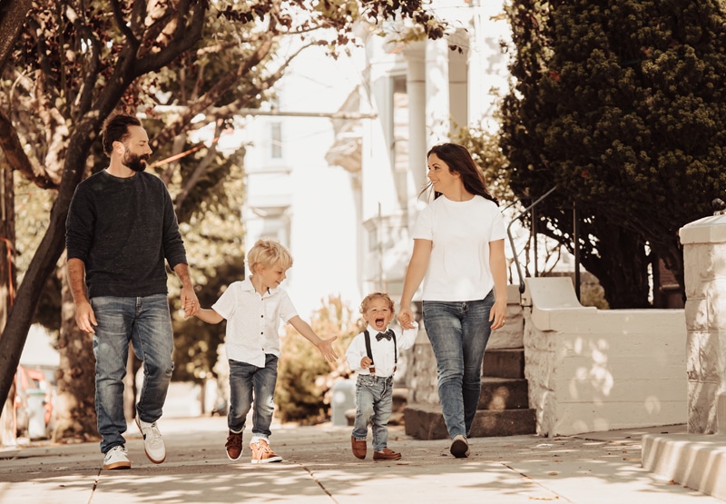 Family Photographer, two parents and their two sons walk through a residential neighborhood in the city