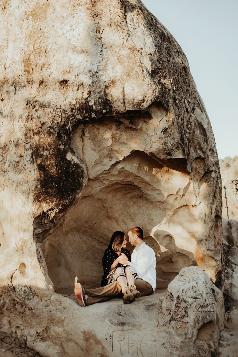 Couples Photographer, man and woman sit in a wind carved rock