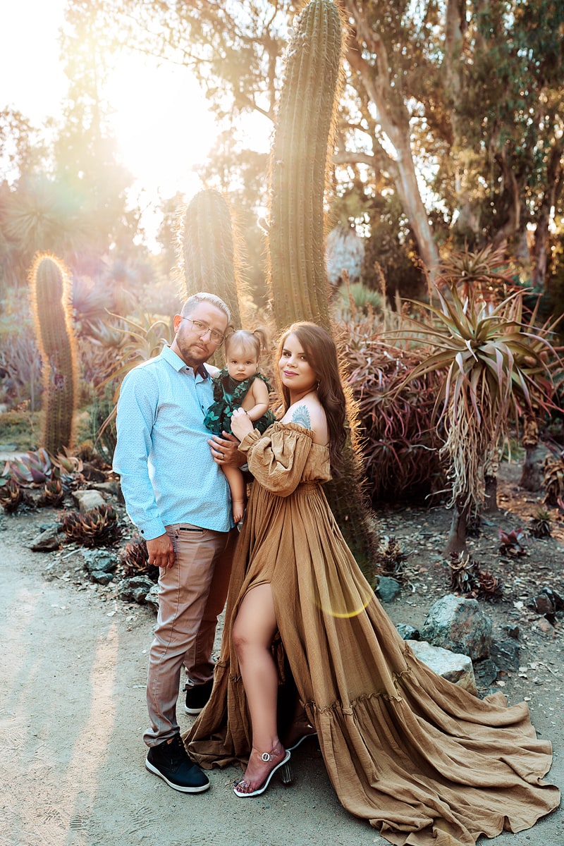 Family Photographer, dad and mom hold their baby girl in a cactus garden