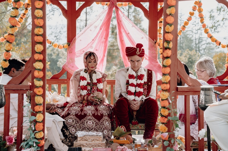 Wedding Photographer, husband and wife to be sit during traditional Hindu wedding ceremony