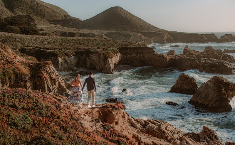 elopement photographer,  man and woman walk hand in hand on a seaside trail