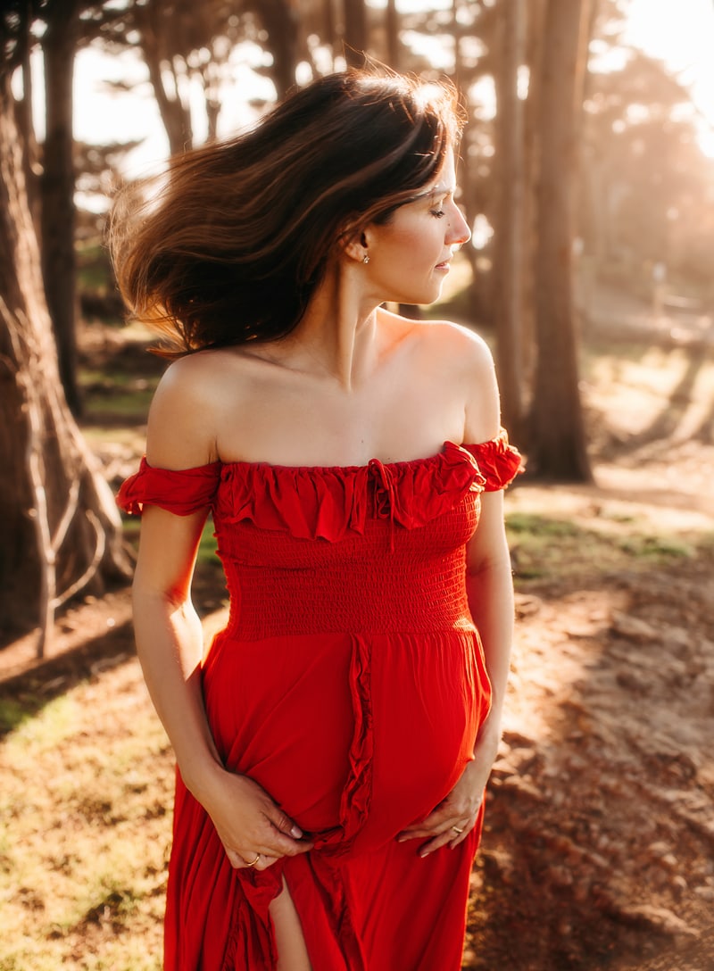 Maternity Photographer, an expecting mother wears a dress and walks through the forest