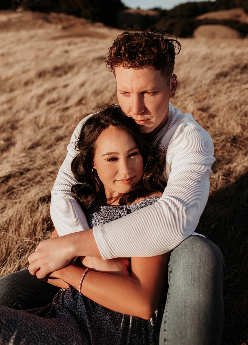 Couples Photographer, man and woman hold each other on a dry grassy hillside