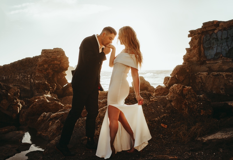 Couples Photographer, man kisses woman hand near the ocean