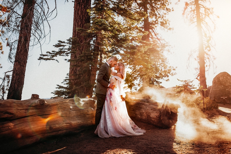 Wedding & Elopement Photographer, Bride and groom stand before Sequoia Log in forest embracing