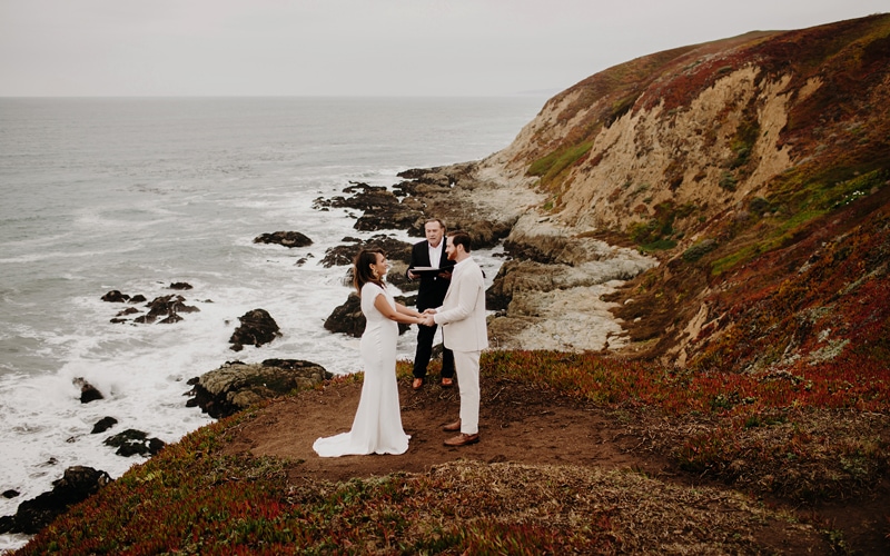 elopement photographer, a man and woman participate in their wedding ceremony near the ocean