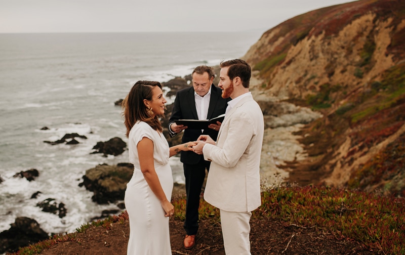Wedding and Elopement Photographer, a man and woman say their vows with officiant on seaside cliffs