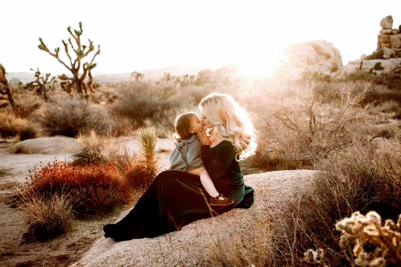 Maternity Photographer, expecting mother kisses daughter in the desert