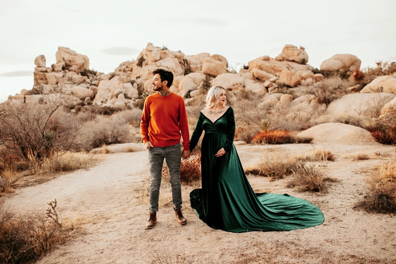 Maternity Photographer, a man and his expecting wife stand happily in the desert