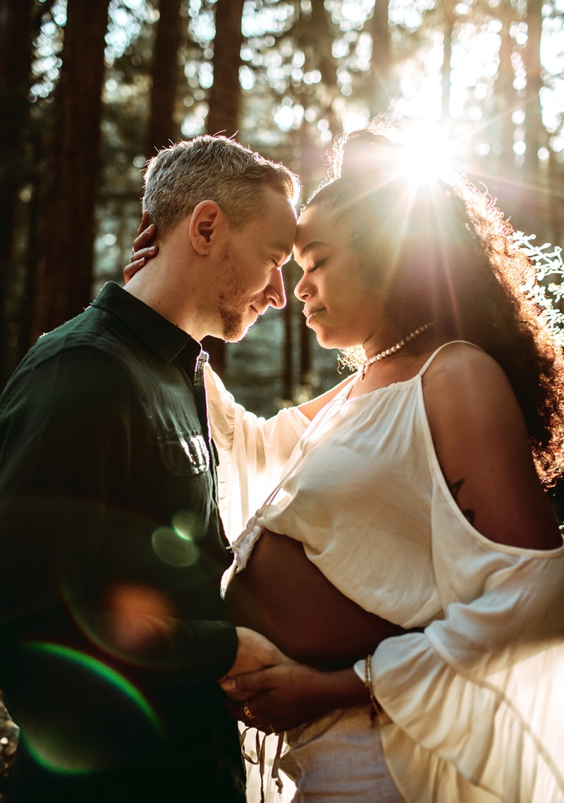 Maternity Photographer, husband and pregnant wife embrace in the forest