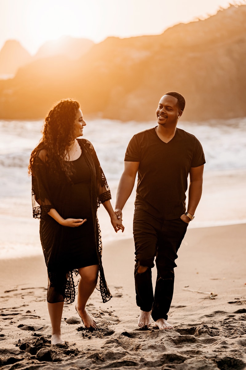 Maternity Photographer, husband and expecting wife walk hand in hand on the beach