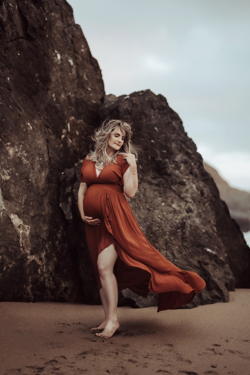 Maternity Photographer, a pregnant woman walks in the sand near the ocean