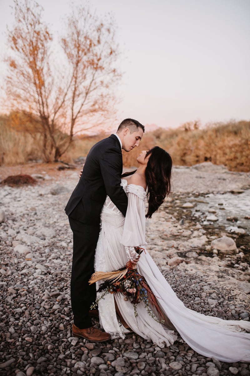Elopement photographer, man and woman stand near a river's edge