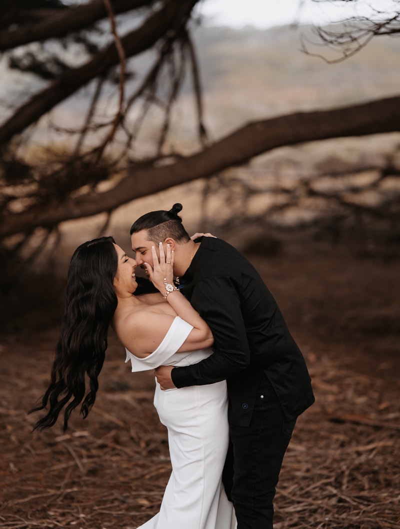 Couples Photographer, man and woman kiss in the outdoors underneath a large tree