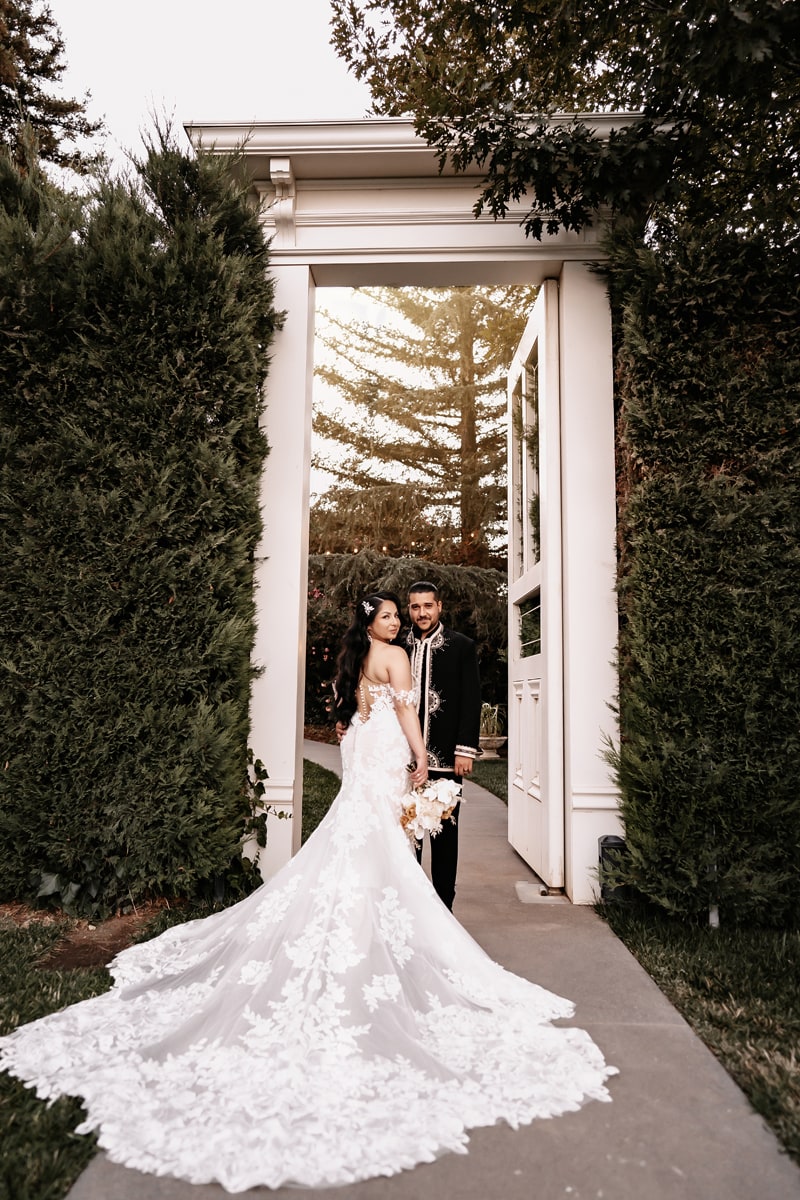 Wedding Photographer, husband and wife stand within a large arch doorway in garden
