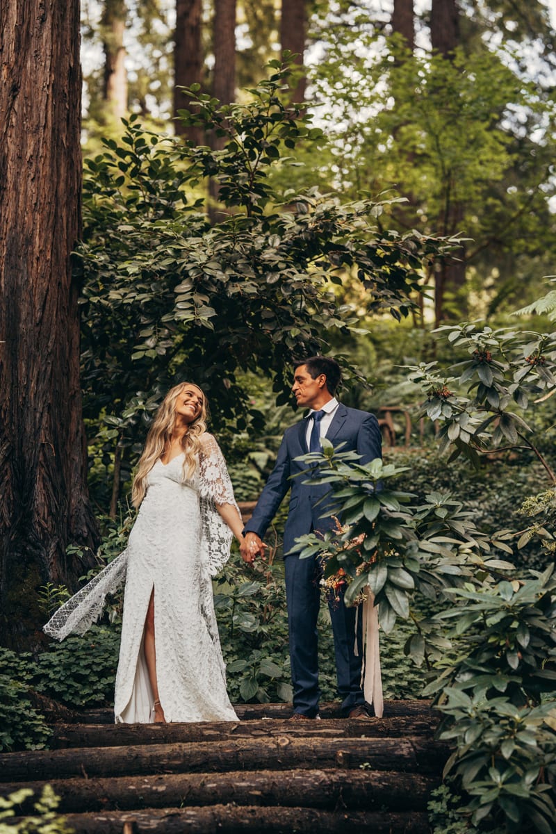 Elopement Photographer, husband and wife hold hands happily as they stand in forest