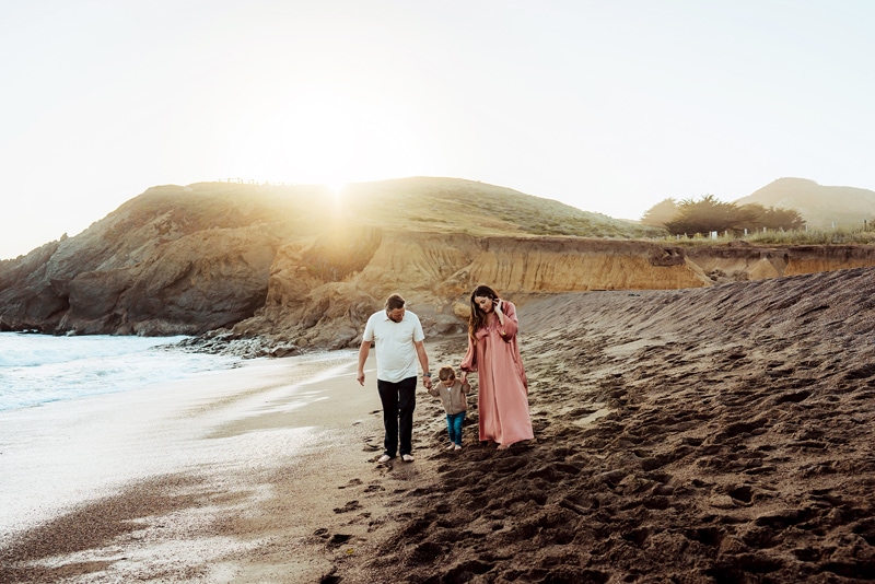 Maternity Photographer, expecting mom and dad walk with child on the beach